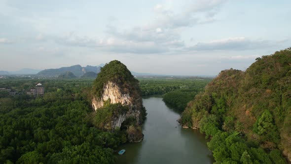 aerial drone flying backwards revealing a river running between a two large green limestone mountain