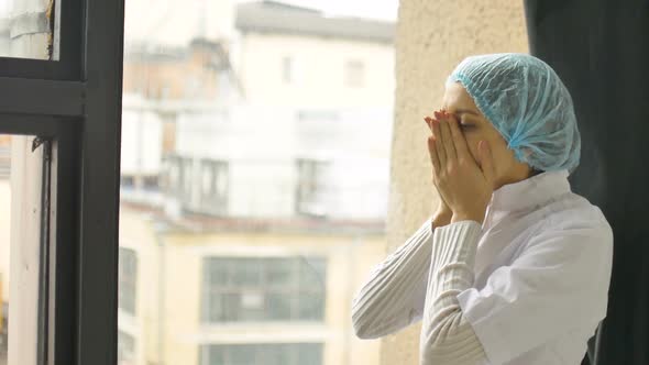 Portrait of Unhappy Tired Young Doctor Having Headache Near a Window