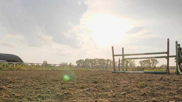 A Woman Jockey Jumps Over the Barriers on a Horse During Sunset, Slow Motion