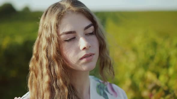 Portrait of Young Thoughtful Lady in Dress Looking at Camera in Summer Field