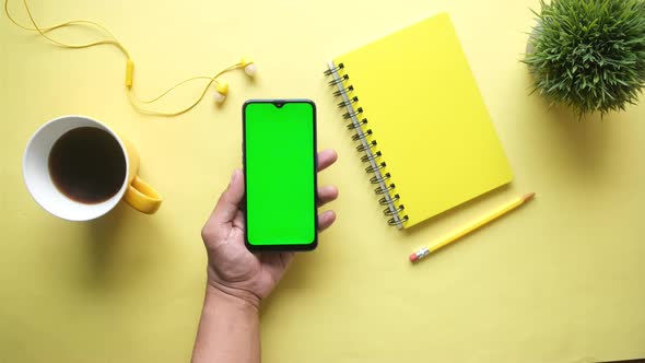 Top View of Man Hand Using Smart Phone on Yellow Background