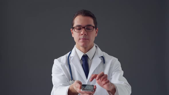 Studio portrait of young professional medical doctor standing over grey background