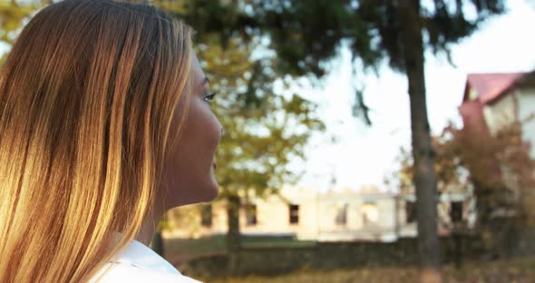 Portrait of Happy Girl Turns at Camera and Smiles in Sunny Autumn