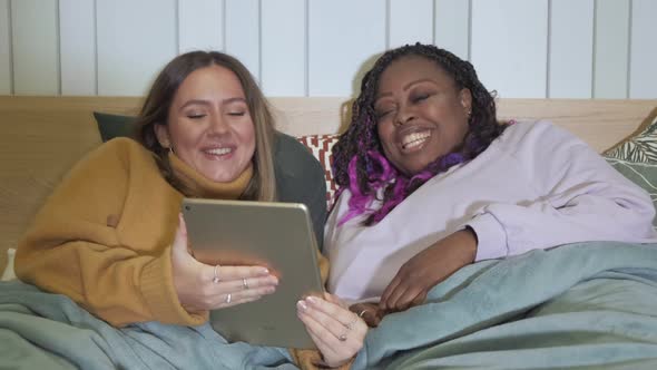 Women Lying On The Bed Watching Videos Using A Tablet, Home Environment, Cozy Apartment