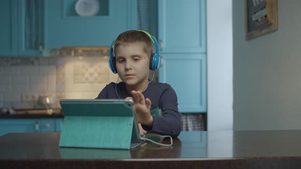 Autistic boy using tablet computer with headphones on the kitchen