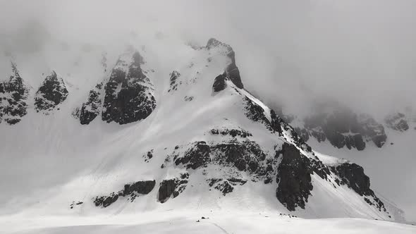 High Altitude Rocky Snowy Mountain Wall in Overcast Winter Day