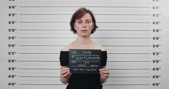 Portrait of Millennial Woman Withshort Haircut Holding Sign for Photo in Police Department