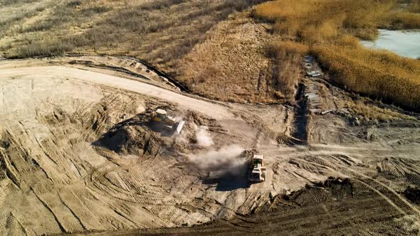 Bulldozersing mounds of dirt on a large construction site - aerial view