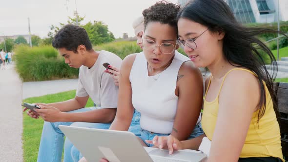 Group of young diverse multiethnic friends outdoor using smartphone