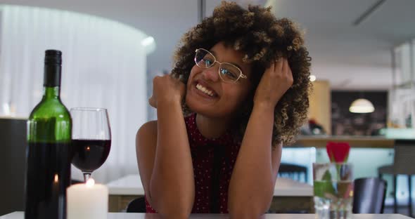 Mixed race woman having a romantic dinner blowing kisses on video chat at home