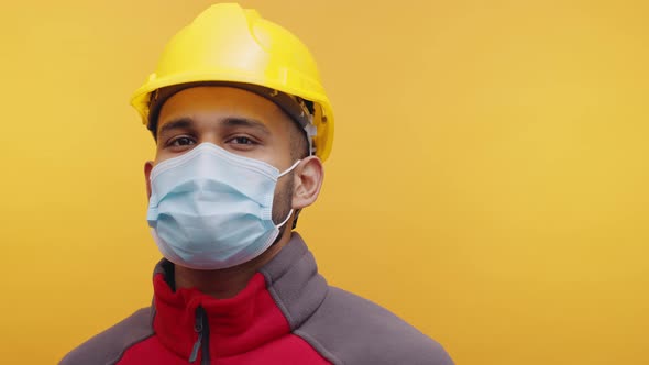 Portrait of Young Indian Man with Face Mask and Yellow Helmet Nodding His Head