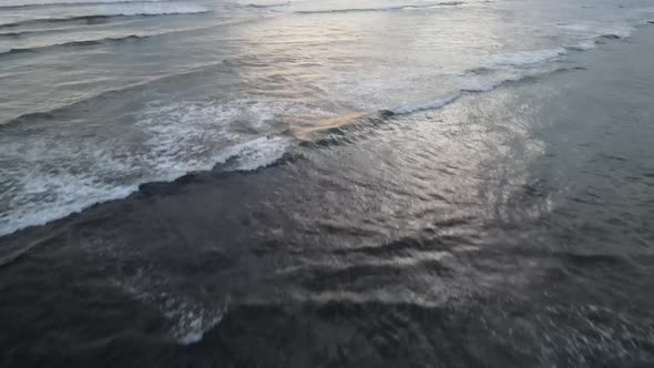 Aerial view of people surfing on waves during sunset when vacation in Bali, Indonesia.