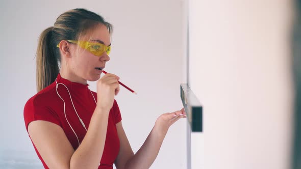 Pretty Woman Checks Wall Level Using Instrument in Room