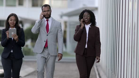 Smiling Managers Walking on Street and Talking on Smartphones