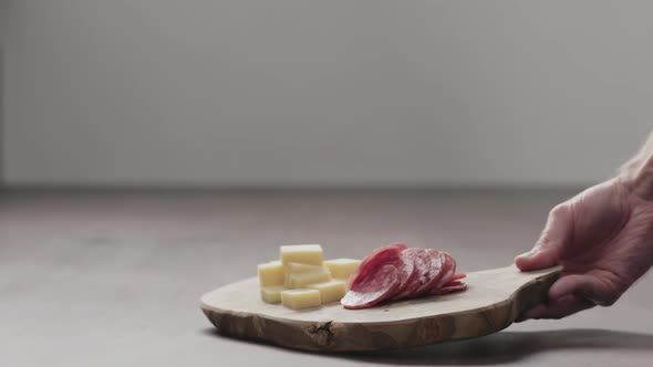 Slow Motion Man Put Olive Board with Vintage Cheese and Salae on Walnut Table