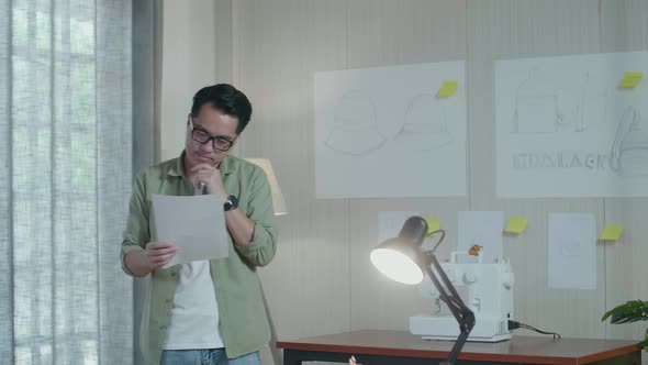 Asian Man Designer Thinking While Looking At The Layout Bond And Walking In The Office