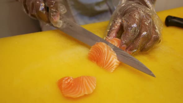 Chief Cutting Raw Salmon Fillets on a Yellow Table