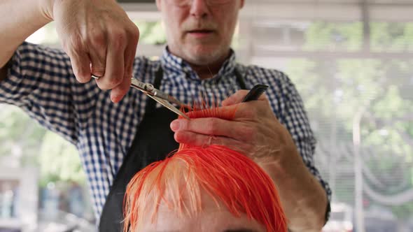 Front view hairdresser cutting woman hair