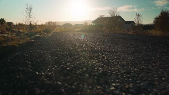 Low angle moving down a gravel road at sunset - animal POV close to the ground