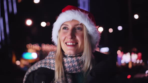 a woman chatting on her smartphone wearing a Santa hat is a night city.