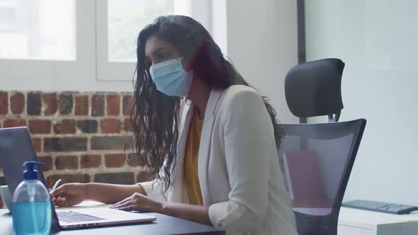 Woman wearing face mask taking notes in office