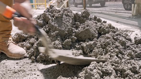 Close-up shot of worker mixing cement with a spade manually