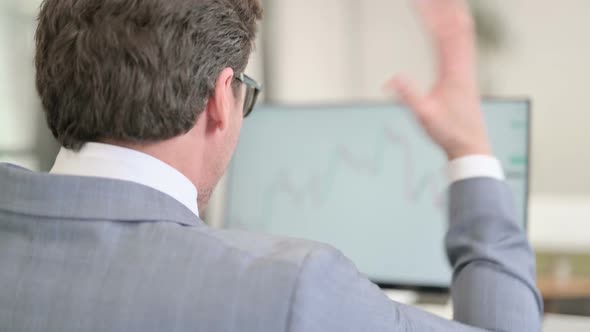 Businessman Looking at Charts on Desktop