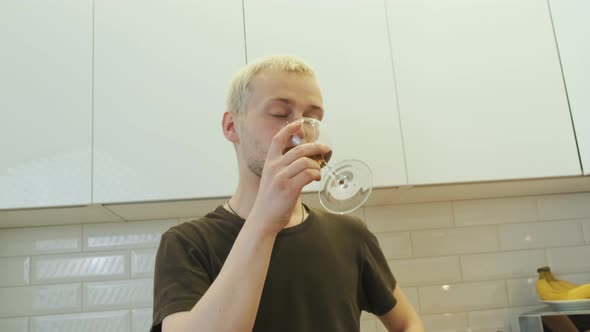 Young Man Enjoys His Glass of Wine in Front of a White Kitchen