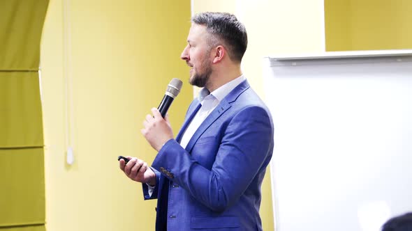Professional speaker in suit with microphone at business conference.