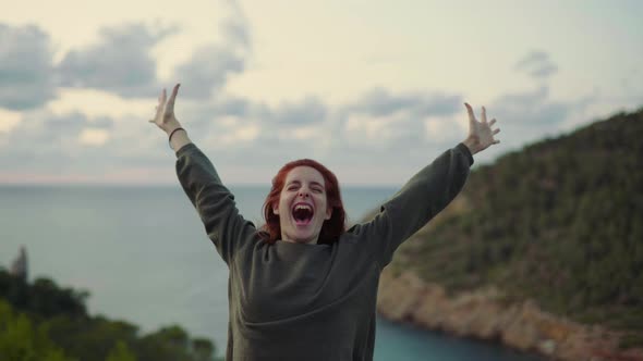 Slow motion shot of happy redheaded woman shouting at the coast