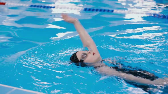 Swimming Lessons for Children in the Pool - Beautiful Fair-skinned Girl Swims in the Water