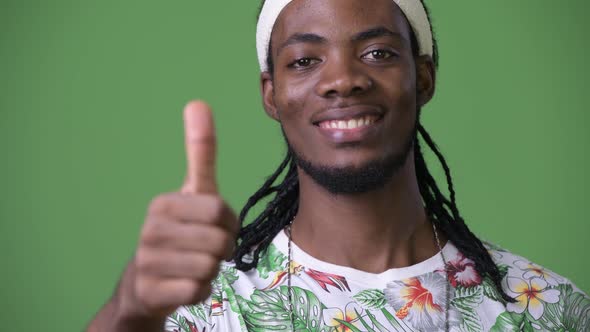 Young Handsome African Man with Dreadlocks Against Green Background