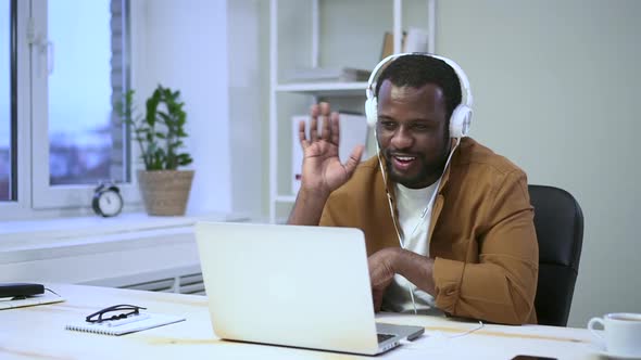 Man Has Online Talk and Waves Hand in Front of Laptop Screen at Table in Room Spbas