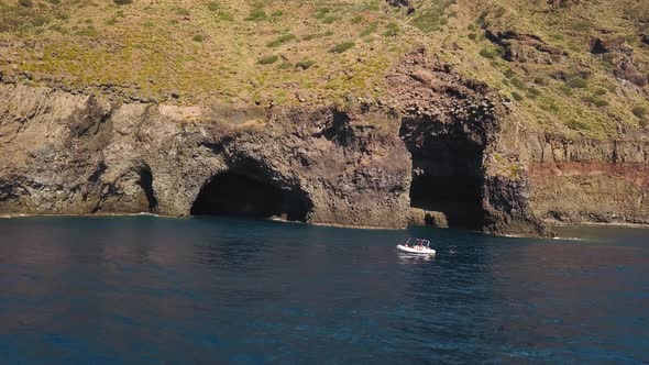 Aerial View on White Boat Anchored Near Cave of Lipari Island in Mediterranean Sea. Some People on