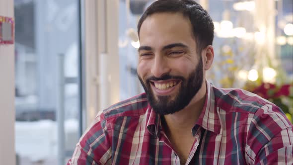 Close-up Face of Cheerful Middle Eastern Man Laughing Out Loud and Drinking Tea in Cafe