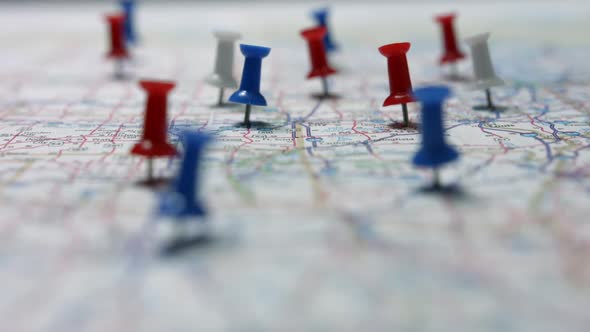 Focus pulls onto red white and blue pins placed marking cities on a US map.