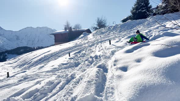 Boy Sled Downhill Having Fun in the Mountains on Winter Vacation