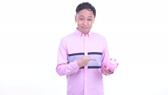 Happy Japanese Businessman Holding Piggy Bank and Giving Thumbs Up