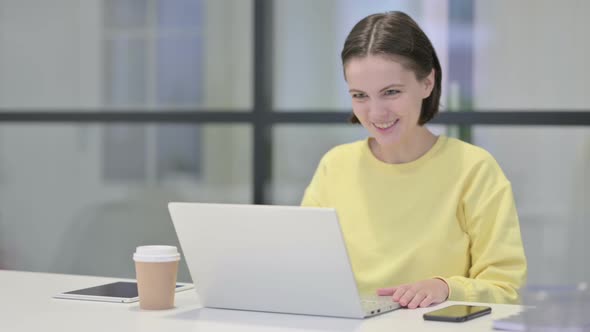 Young Woman Talking on Video Call on Laptop in Office