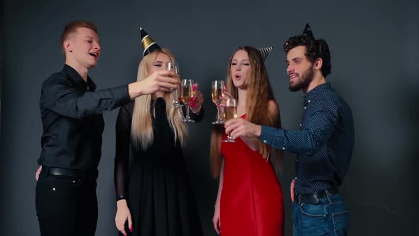 Four Beautiful Friends in Festive Clothes Clinking Glasses with Champagne