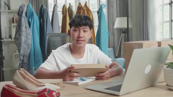 Asian Man Online Seller With Package Look At Camera And Smile While Using Computer For Selling