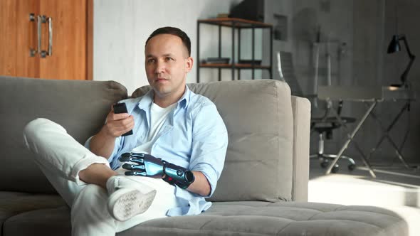 Disabled man with artificial bio hand prothesis switches television channels