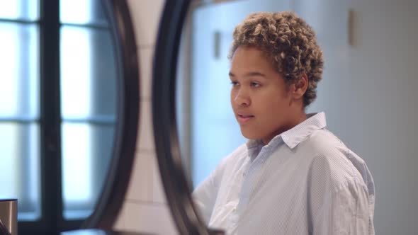 Photo of Cheerful African Woman Smiling While Looking at Mirror in Public Washroom