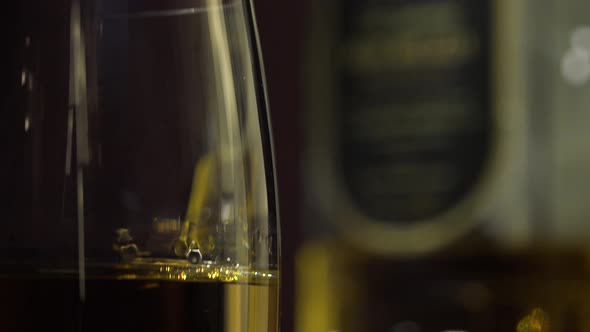 Closeup on a Glass of Whiskey - a Bottle in the Blurry Background