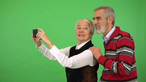 An Elderly Couple Takes a Picture of Something Off the Camera with a Smartphone