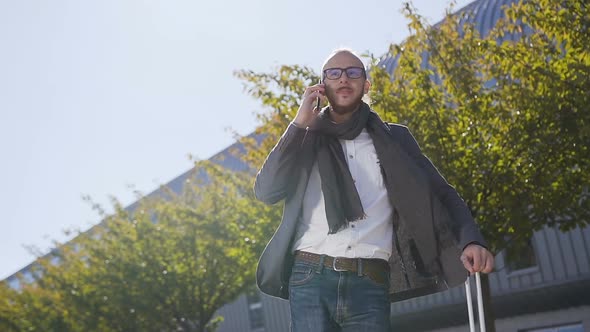 Young bearded businessman dressed in jacket is talking on phone