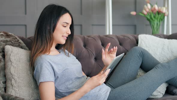 Young Pretty Woman Sitting on Sofa with Tablet Pc