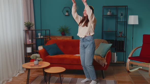 Pretty Caucasian Young Woman in Headphones Listening Music Dancing Singing in Living Room at Home