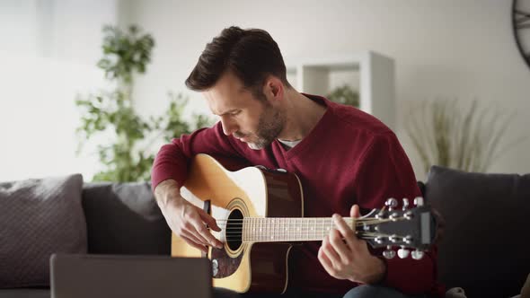 Video of man playing acoustic guitar at home. Shot with RED helium camera in 8K.