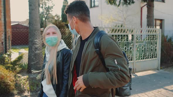 Blonde Woman and African Man in Protective Masks Strolling Through the Residential Area